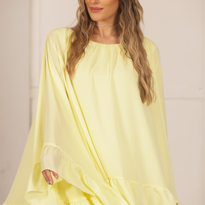 Vestido amarelo claro com folhos, usado por mulher com cabelo ondulado e grampo dourado