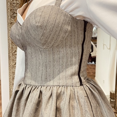 Vestido cinza claro brilhante com linhas verticais e botão preto ao lado de espelho decorado