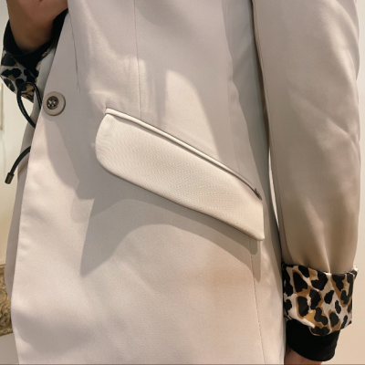 Casaco bege claro com bolso de aba e forro das mangas com padrão animal print.