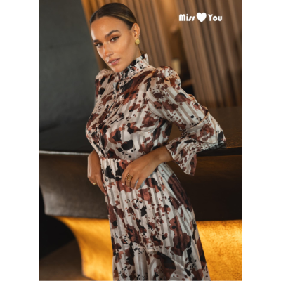 Mulher a usar vestido comprido com padrão castanho e bege e gola alta com folhos