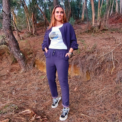 Mulher com conjunto azul-escuro e t-shirt branca com texto num bosque