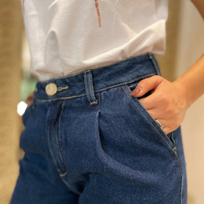 Calças de ganga azuis escuras com bolso frontal e botão branco vistas de perto