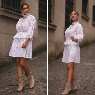 Mulher a desfilar com vestido branco bordado e botins bege