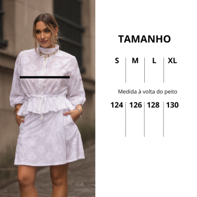 Vestido branco com ilhós e bordados florais, cintura ajustável, mangas bufantes e bolsos, usado por mulher ao ar livre.