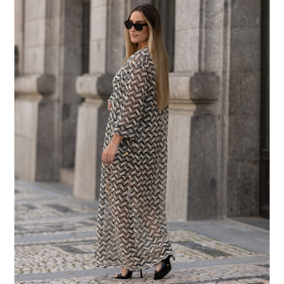 Mulher de vestido transparente preto e branco com padrão geométrico e óculos escuros