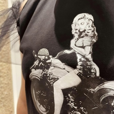 T-shirt preta com estampa de mulher desenhada numa moto em branco e cinza