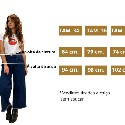 Mulher vestindo calças de ganga largas azuis com botas pretas e t-shirt branca, tabela de medidas para tamanhos 34, 36 e 38