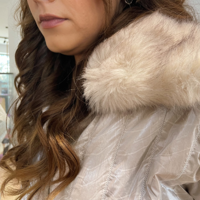 Casaco bege claro com capuz de pelo sintético creme em mulher com cabelo castanho ondulado