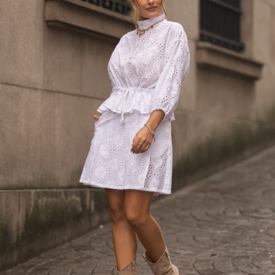 Vestido branco rendado com padrão floral e botas bege em rua de pedra