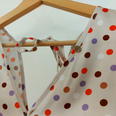 Vestido bege com bolinhas coloridas pendurado em cabide de madeira