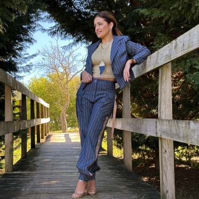 Mulher com fato azul-riscas e sandálias numa ponte de madeira ao ar livre
