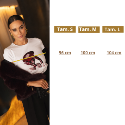 Mulher com camisola branca estampada, casaco de pelo castanho escuro, calças pretas, ao lado tabela de tamanhos em português.