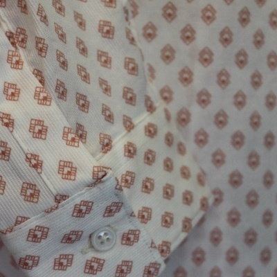 Camisa branca com padrão castanho claro e punho abotoado