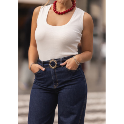 Mulher com regata branca e calças de ganga azul escuro com cinto e colar vermelho
