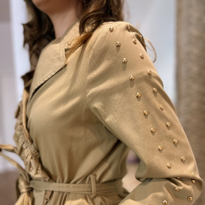 Blusa bege com bolinhas douradas metálicas nas mangas.