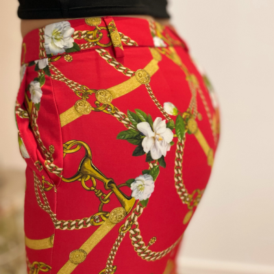 Calças vermelhas com padrões de correntes douradas e flores brancas