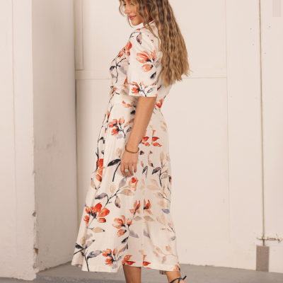 Mulher de perfil a usar vestido midi floral e sandálias verdes de salto