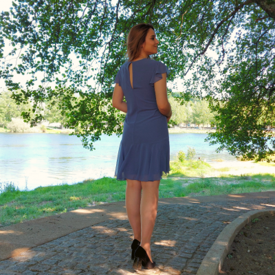 Mulher de costas a usar vestido azul curto junto ao lago