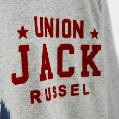 Detalhe de peça de vestuário cinzenta com texto vermelho Union Jack Russel