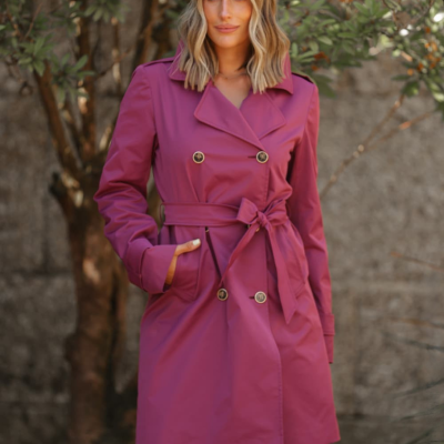 Mulher com casaco rosa estilo trench coat com botões e cinto, outdoors