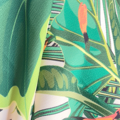 tecido estampado tropical com folhas verdes e detalhes laranja