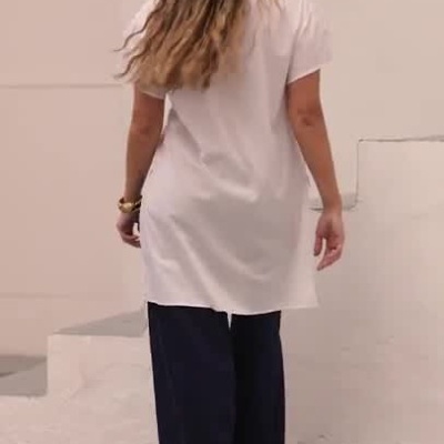 Mulher a usar camisa branca longa e calças largas escuras