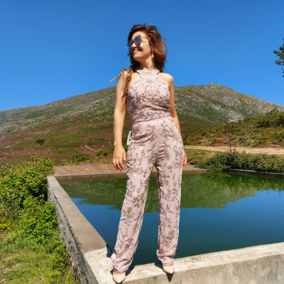 Macacão rosa claro com padrão floral usado por mulher ao ar livre junto a piscina