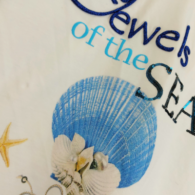 T-shirt branca com estampa de conchas e texto azul e preto