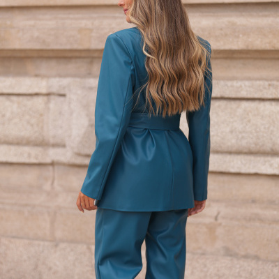 Mulher de costas com conjunto azul turquesa contra parede de pedra