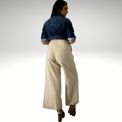 Mulher de costas a usar calças largas geométricas bege e casaco de ganga azul