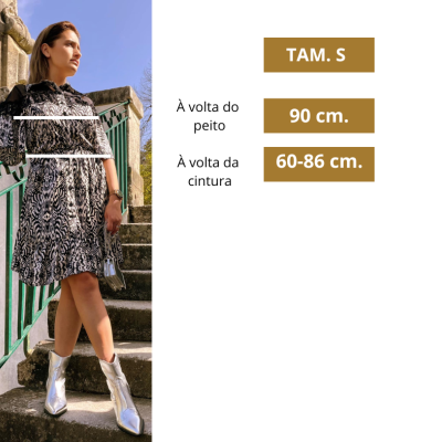 Mulher com vestido animal print preto e branco, tamanho S, em escadas exteriores.