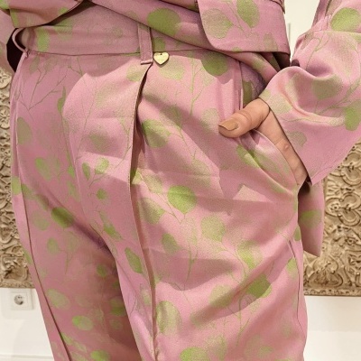 Conjunto rosa com padrão de folhas verdes, botão dourado em forma de coração e bolso lateral.