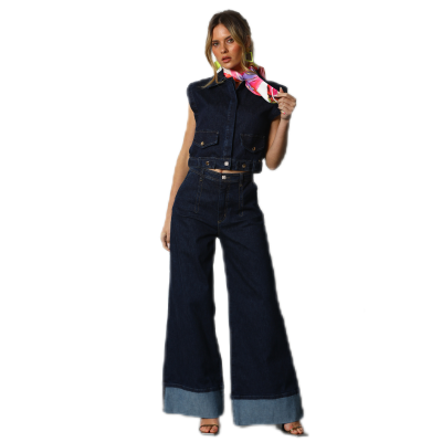 Mulher com colete e calças de ganga azul escuro largas, com lenço colorido no pescoço