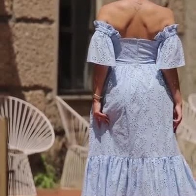 Mulher a desfilar em vestido azul claro com folhos na rua exterior