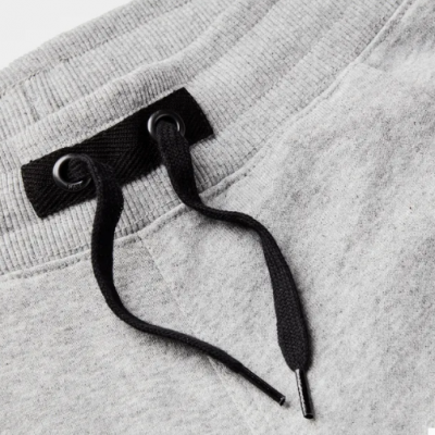 Pormenor de calças de fato de treino cinza claro com cordões pretos no cós