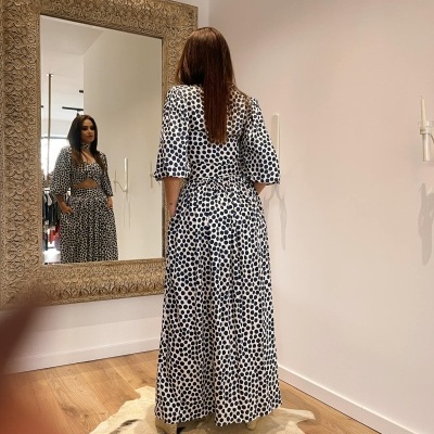 Vestido comprido branco com bolinhas pretas em mulher refletida no espelho