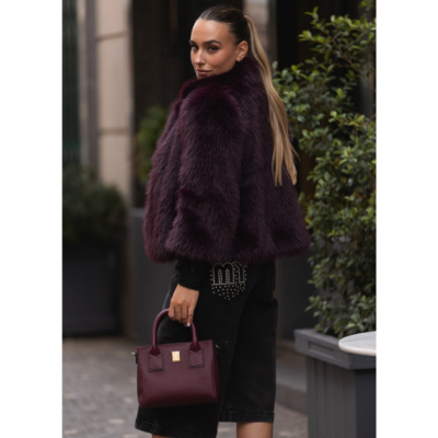 Mulher com casaco de pêlo borgonha, calções pretos com a palavra LOVE em tachas e mala de mão borgonha