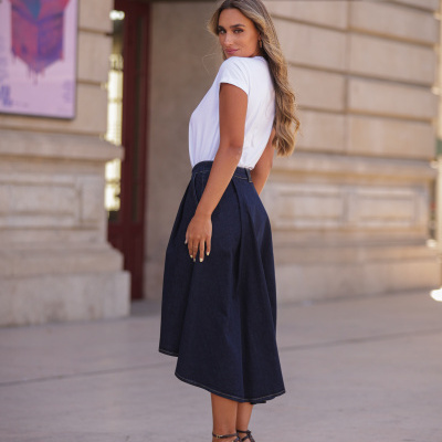 Mulher de costas com camisa branca, saia azul escura e sapatos castanhos de salto alto