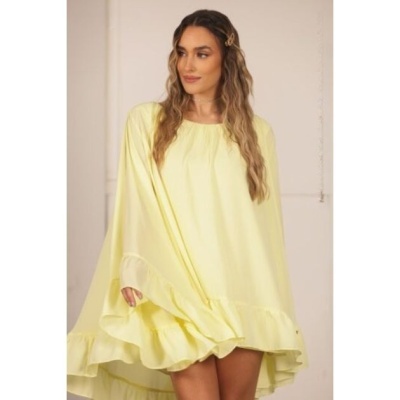 Mulher com vestido amarelo claro com babados numa sala neutra