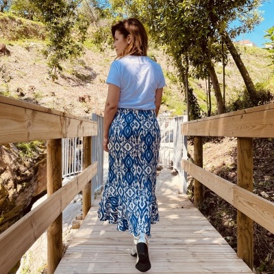 Vestido longo azul e branco com padrão geométrico numa ponte de madeira ao ar livre