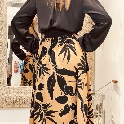 Vestido preto com saia bege estampada em ambiente interior com espelho
