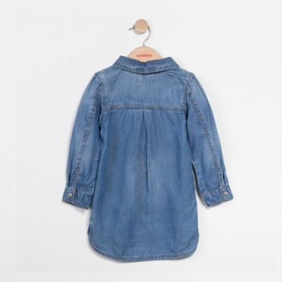 Vestido camisola azul claro de ganga pendurado numa cabide de madeira