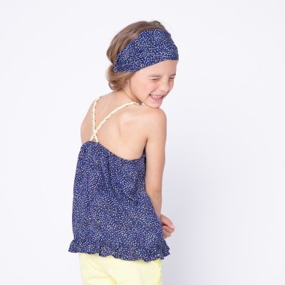 Garota com top azul estampado, calções amarelos e faixa de cabelo azul