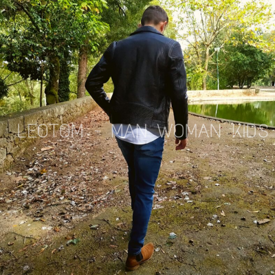 Homem a caminhar numa área exterior com casaco preto de pele e calças azuis