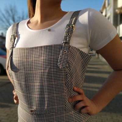 Pessoa com vestido xadrez e top branco em ambiente urbano exterior