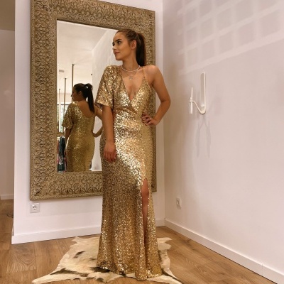 Vestido longo dourado com lantejoulas, um ombro com manga, decote em V e fenda frontal