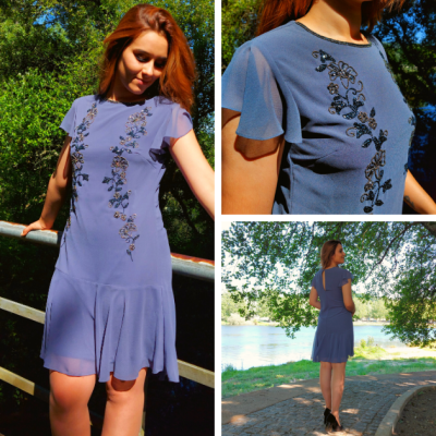 Vestido azul claro com bordados florais pretos usado por mulher ao ar livre junto a lago