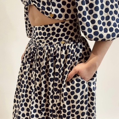 Conjunto creme com bolinhas pretas com saia plissada com bolso e camisa de botões dourados