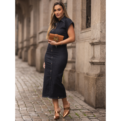 Mulher com vestido de ganga azul escuro e mala castanha em ambiente urbano