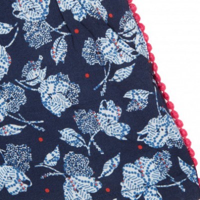 Tecido azul escuro com padrão floral branco e azul e bordado vermelho em pompons